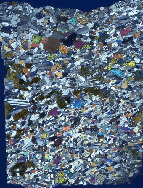 4 cm long thin section of one of Jürgen’s gabbros from Oman. (Grey grains are plagioclase crystals; the brightly coloured grains are olivine and clinopyroxene crystals.