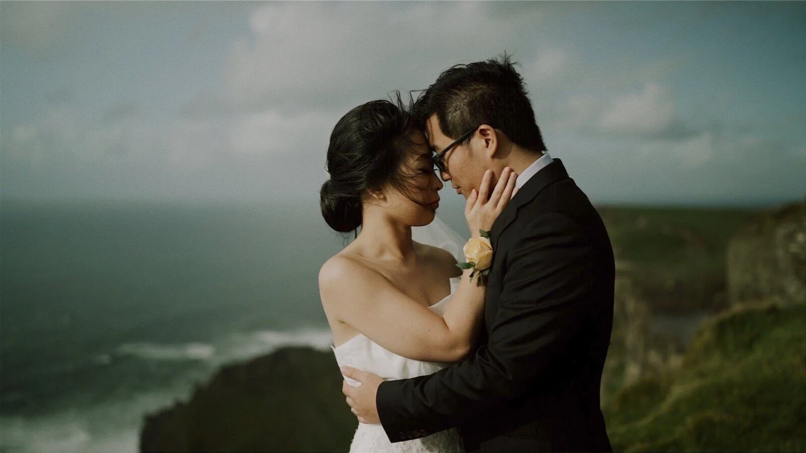 Elopement couple embracing with the Atlantic coast behind them at the Cliffs of Moher