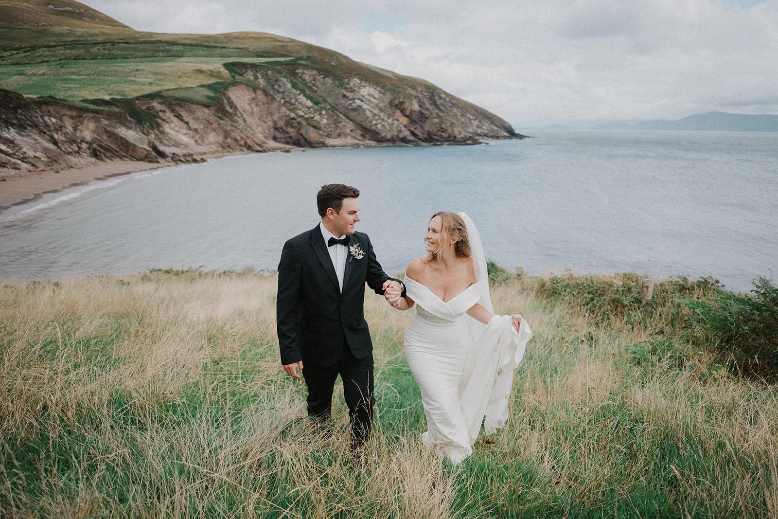 Newlywed couple walking above the coast during their elopement in Dingle, Ireland.
