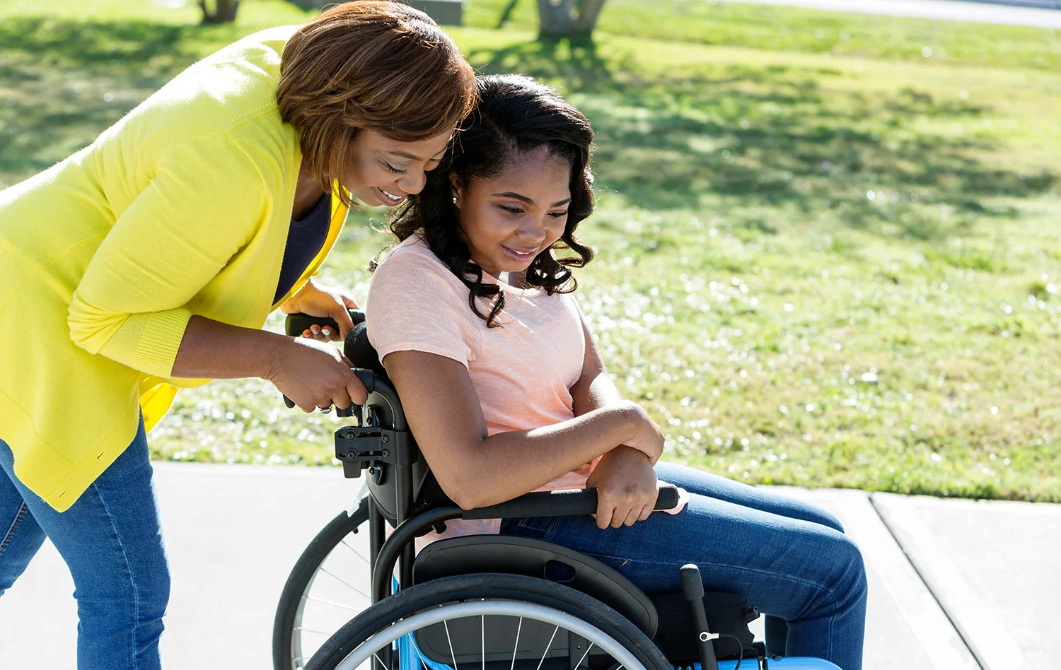 Woman pushes girl in a wheelchair.