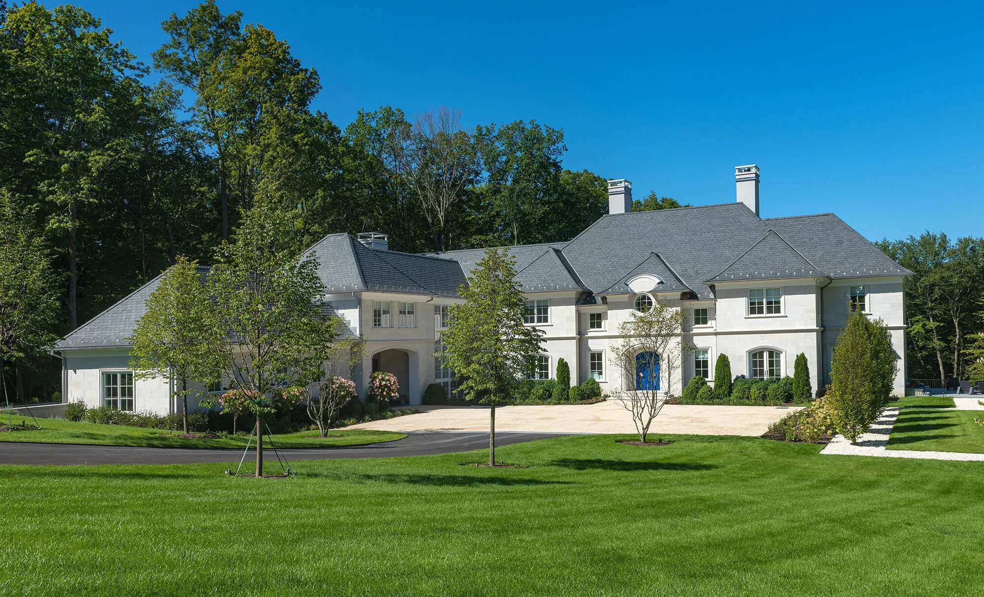 A white chateau-style house with a dark grey roof