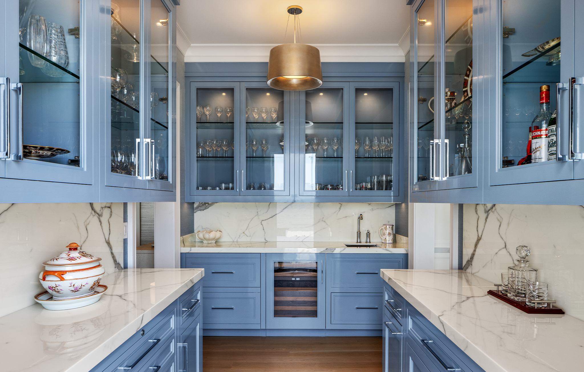 Kitchen with blue cabinets and shelving, accented by white marble countertops and backsplash.