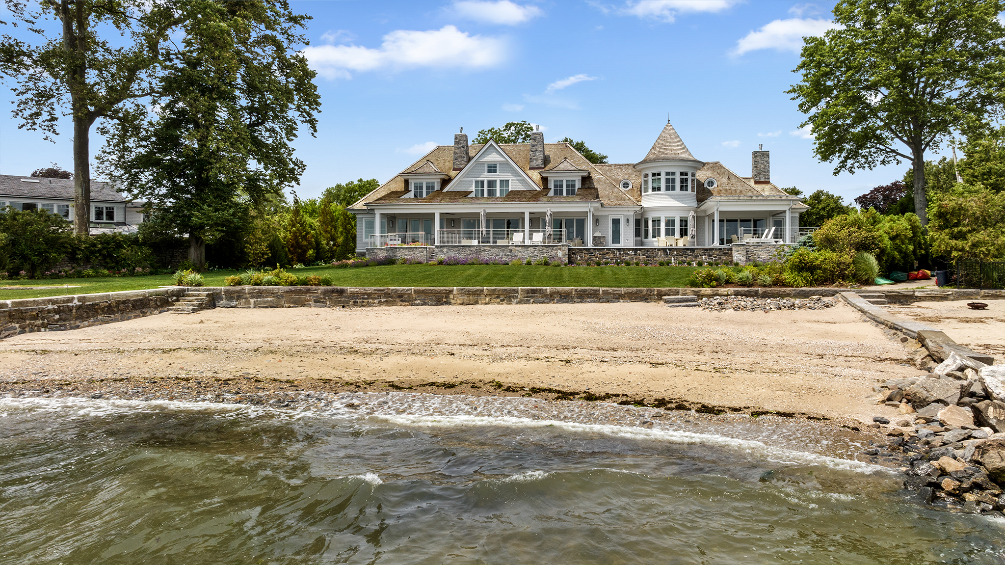 Elegant beachfront mansion with manicured landscaping and private sandy shore