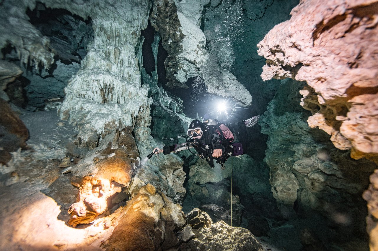 scuba diver surrounded by rock formations in dos ojos