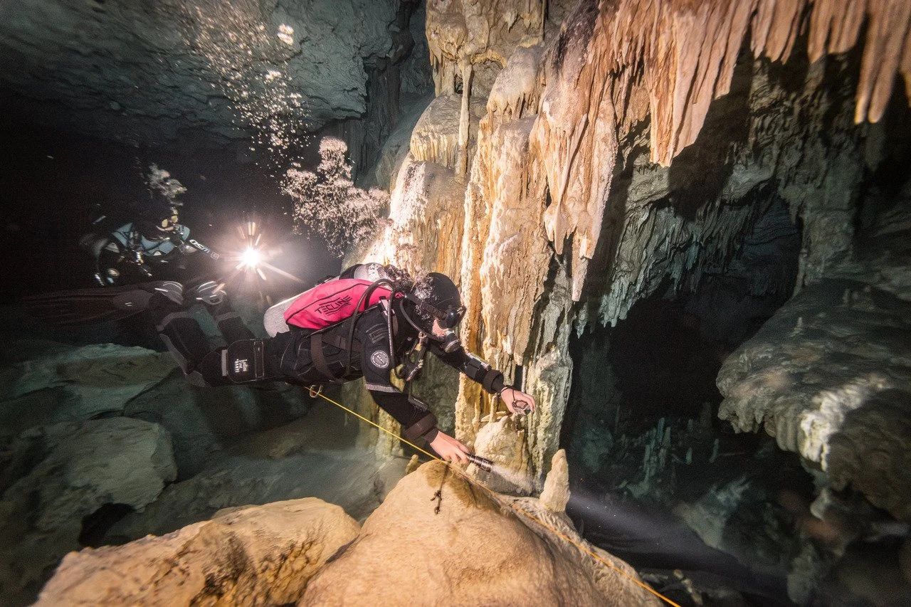 scuba diver admiring the impressive stalactites at dos ojos cenote