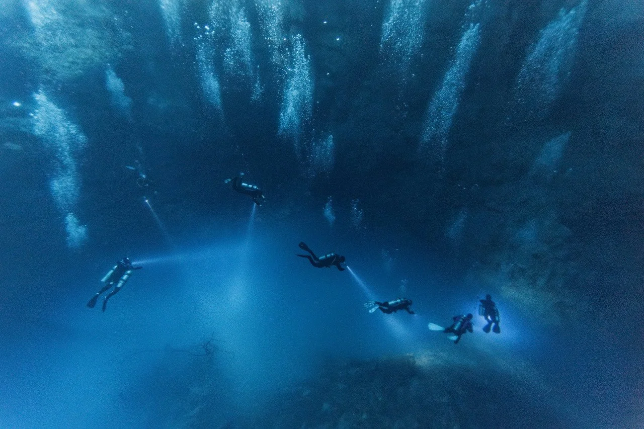 scuba divers descend into el pit cenote