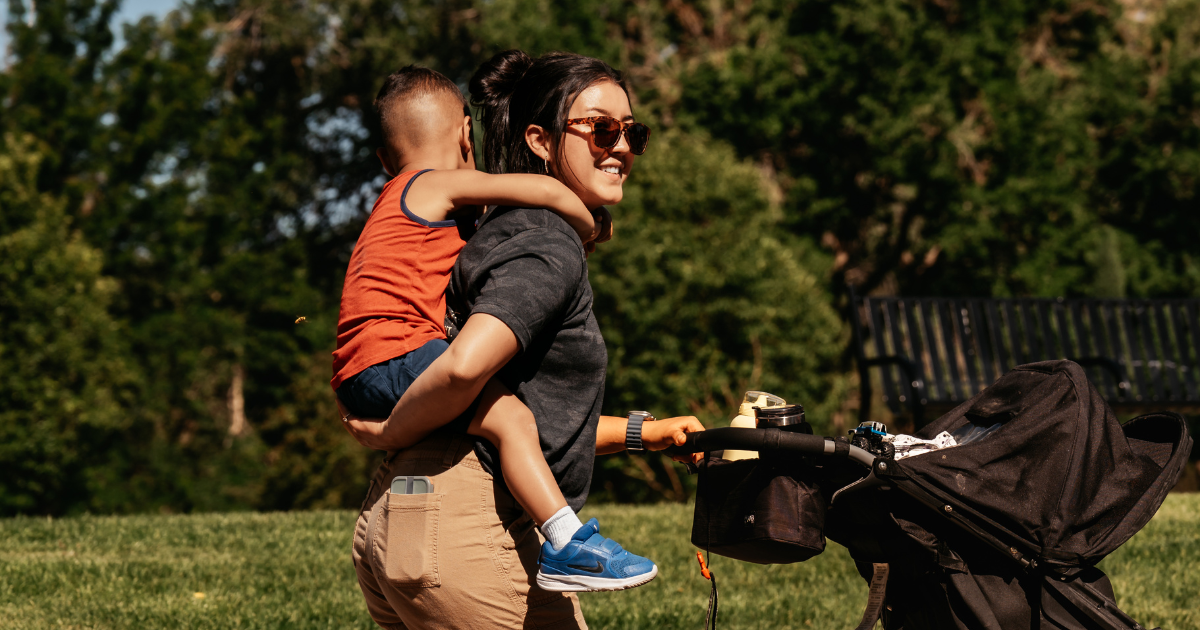 mom carrying child while pushing stroller at walk for life