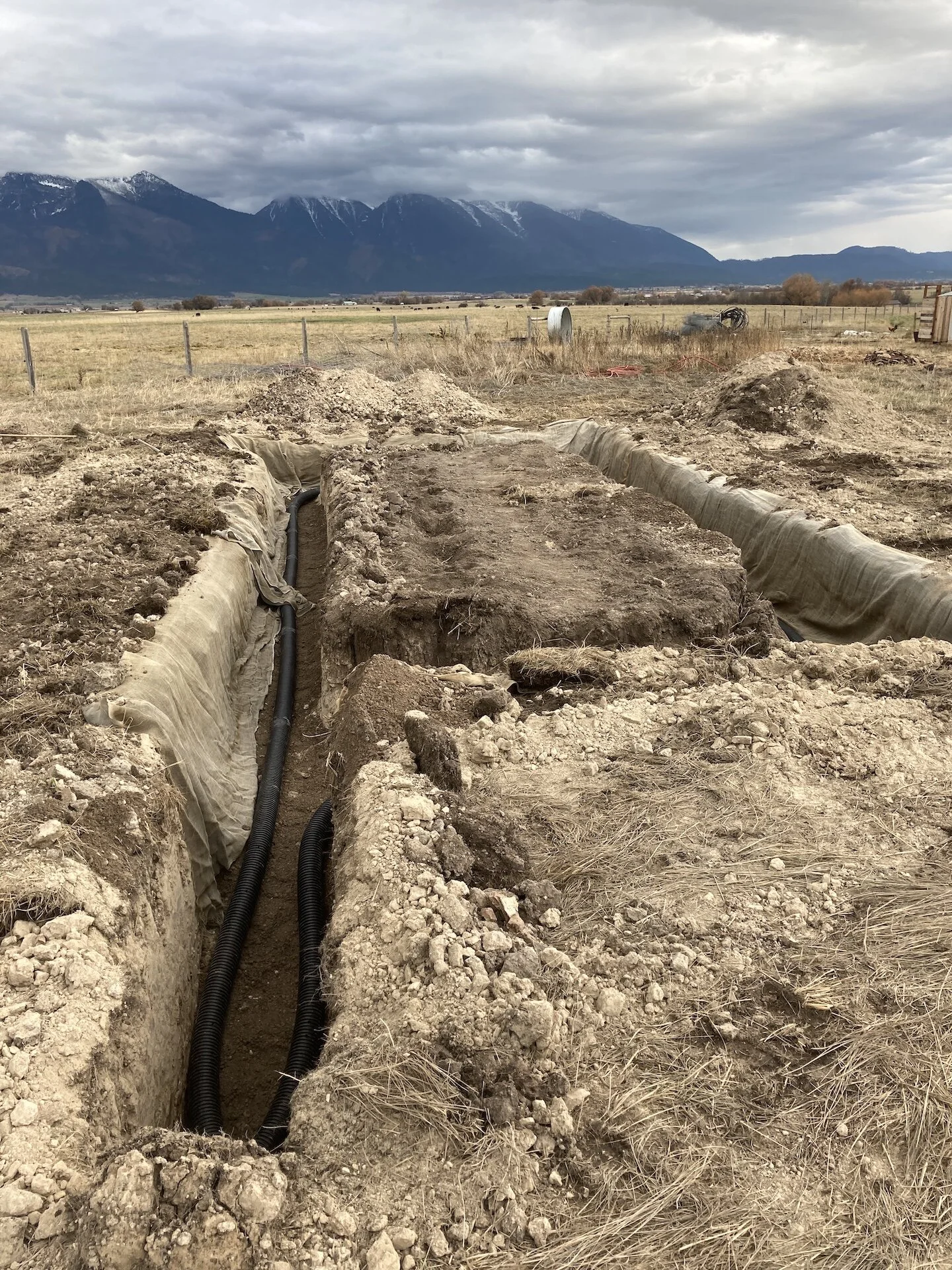  After excavation, the trench was backfilled with sand.  A drainpipe was layed over the sand.  Some burlap was draped to prevent silt migration.  Drain rock was used for the remaining fill up to just below grade.  