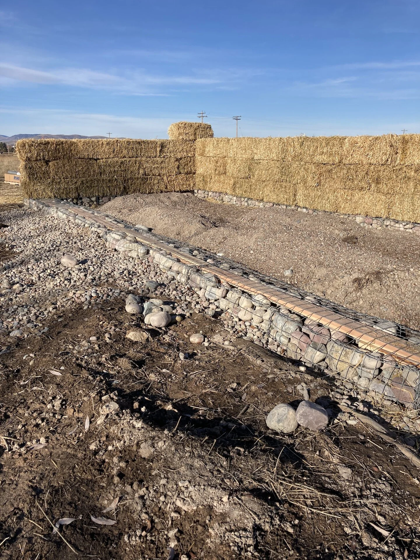  The bale walls went up quickly.  Bales were picked up locally, we bought ~ 120-ish.  Note the 2X6’s set into the Gabions on the south end.  This is so the south framed wall could be screwed into the foundation. 
