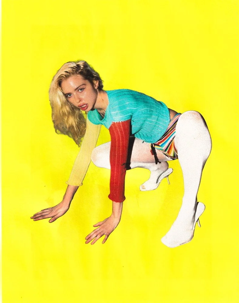 A woman with blond hair crouches on the ground against a bright yellow background, wearing colorful clothing including a multi-colored sweater and striped shorts, along with white high-heeled boots.