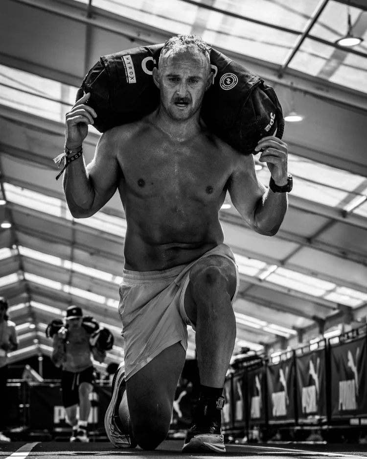 Steven Fiello carrying a sandbag lunge at HYROX NYC