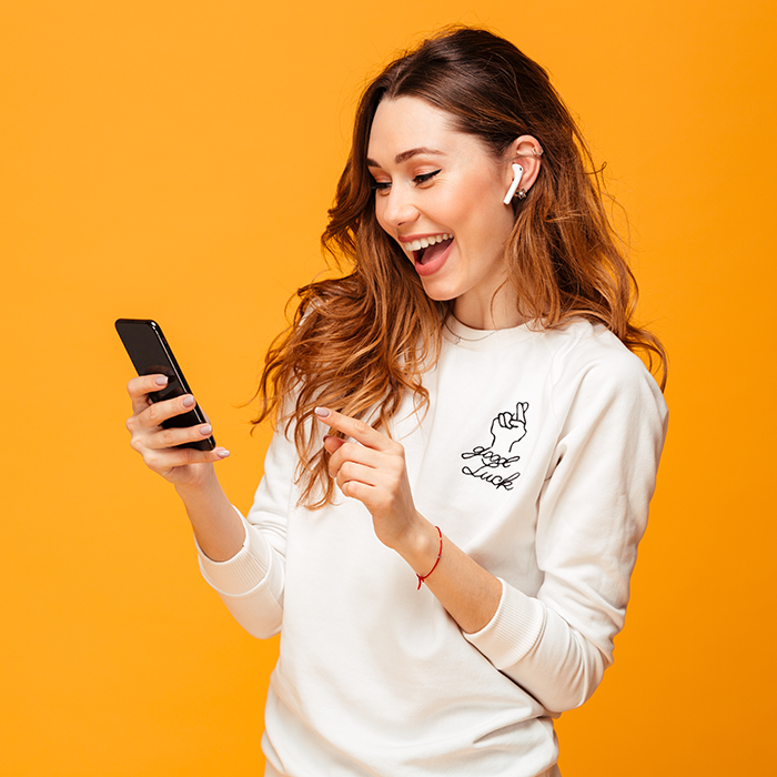 Woman smiling tapping phone orange bg.png