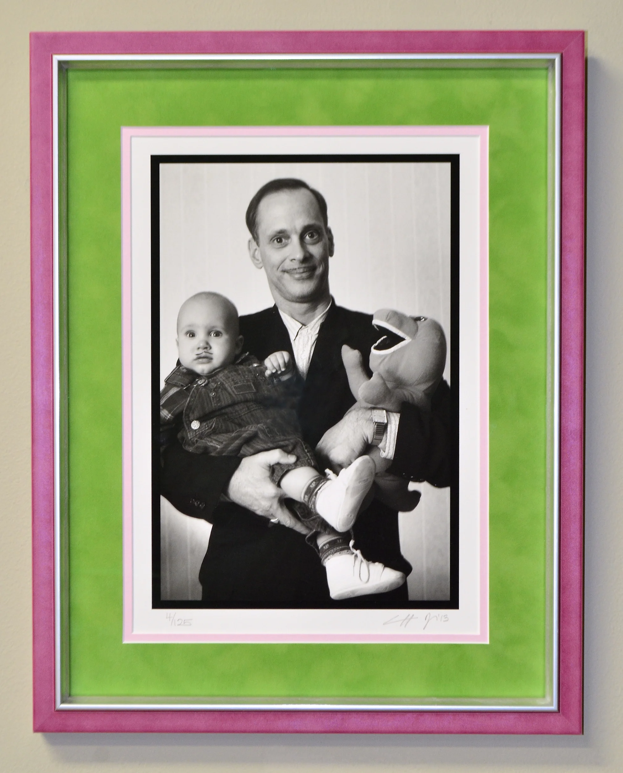  framed photograph portrait of film director John waters holding a baby with barney dinosaur doll mustached black white monochrome 