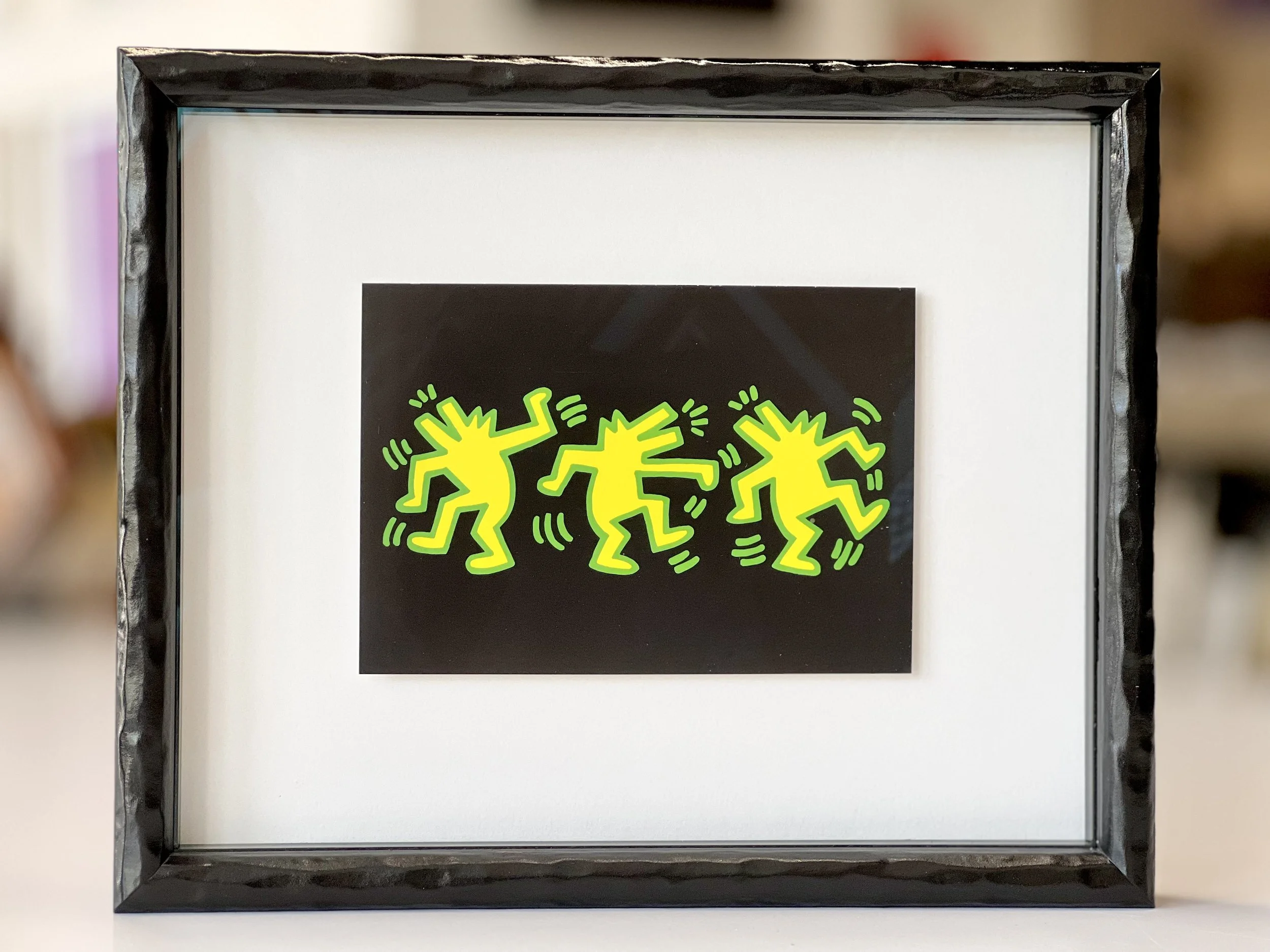 framed art postcard three dancing yellow green dogs by street artist Keith haring in graffiti style 1980s pop art