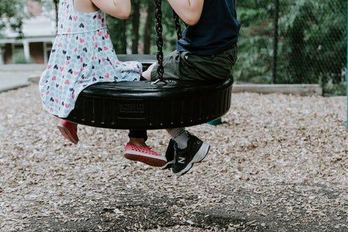 two children playing on tire swing.jpeg