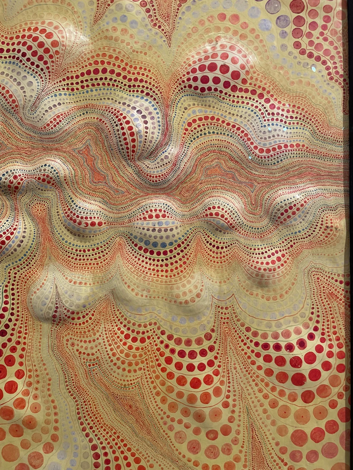  Detail of Minoru Onoda’s  WORK62-W  (1962), showing flowing, topographic bands of red and orange dots with blue accents on a pale yellow-green ground. 