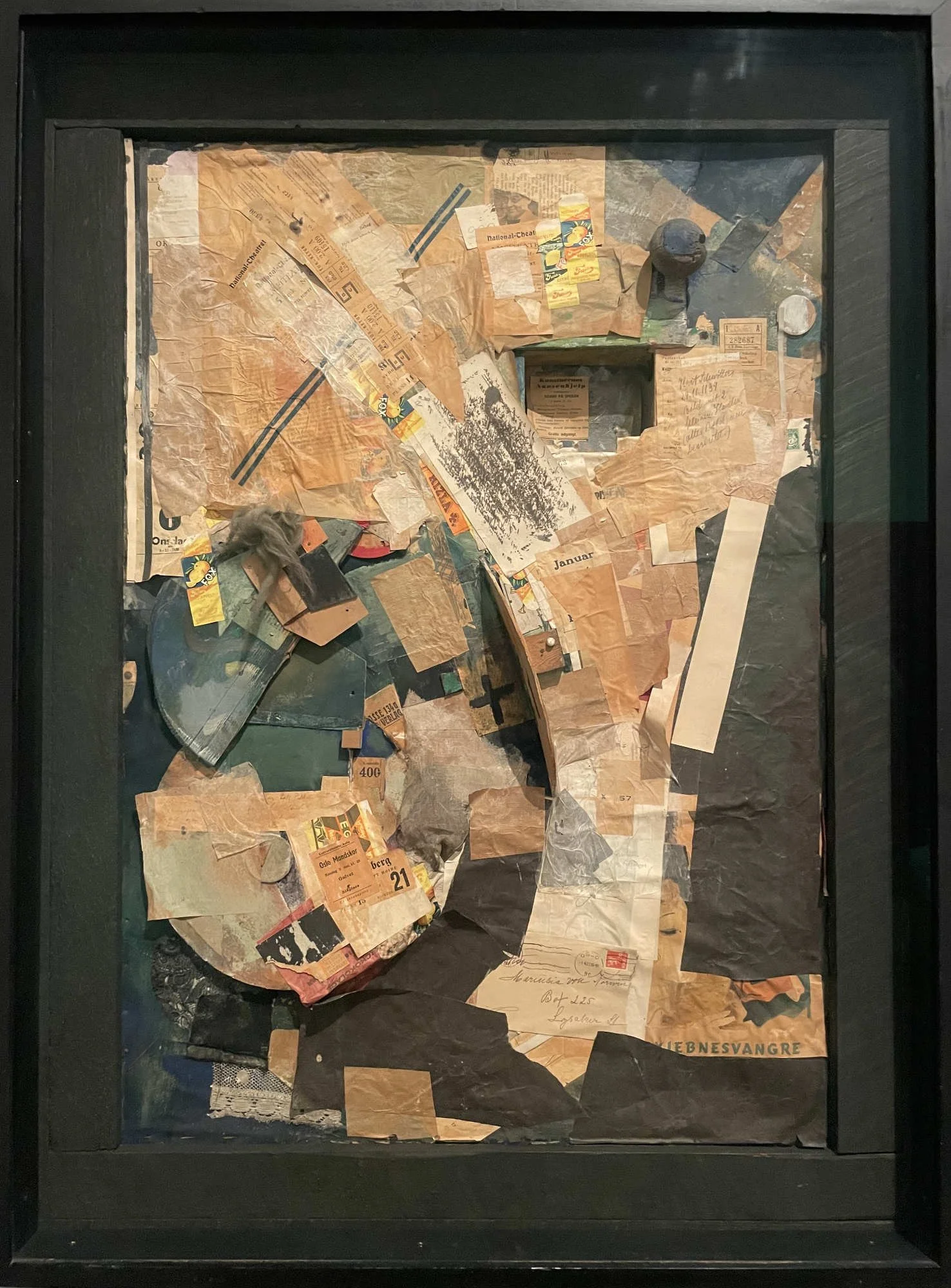  Kurt Schwitters,  Picture of Spatial Growths - Picture with Two Small Dogs  - mixed-media assemblage of layered torn papers, tickets, receipts, and printed scraps arranged in a dense composition within a dark frame. 