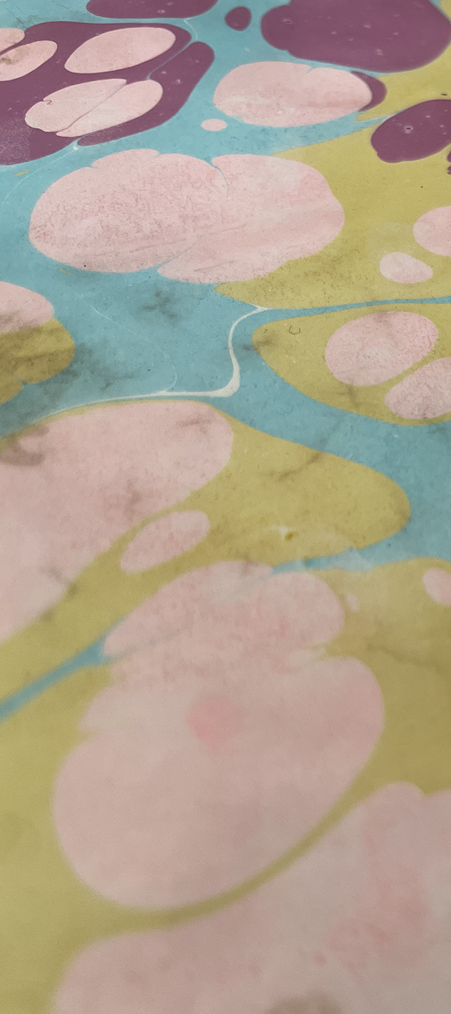 Close-up of a colorful, abstract design with pink, purple, blue, and yellow shapes resembling watercolor splashes or blobs.