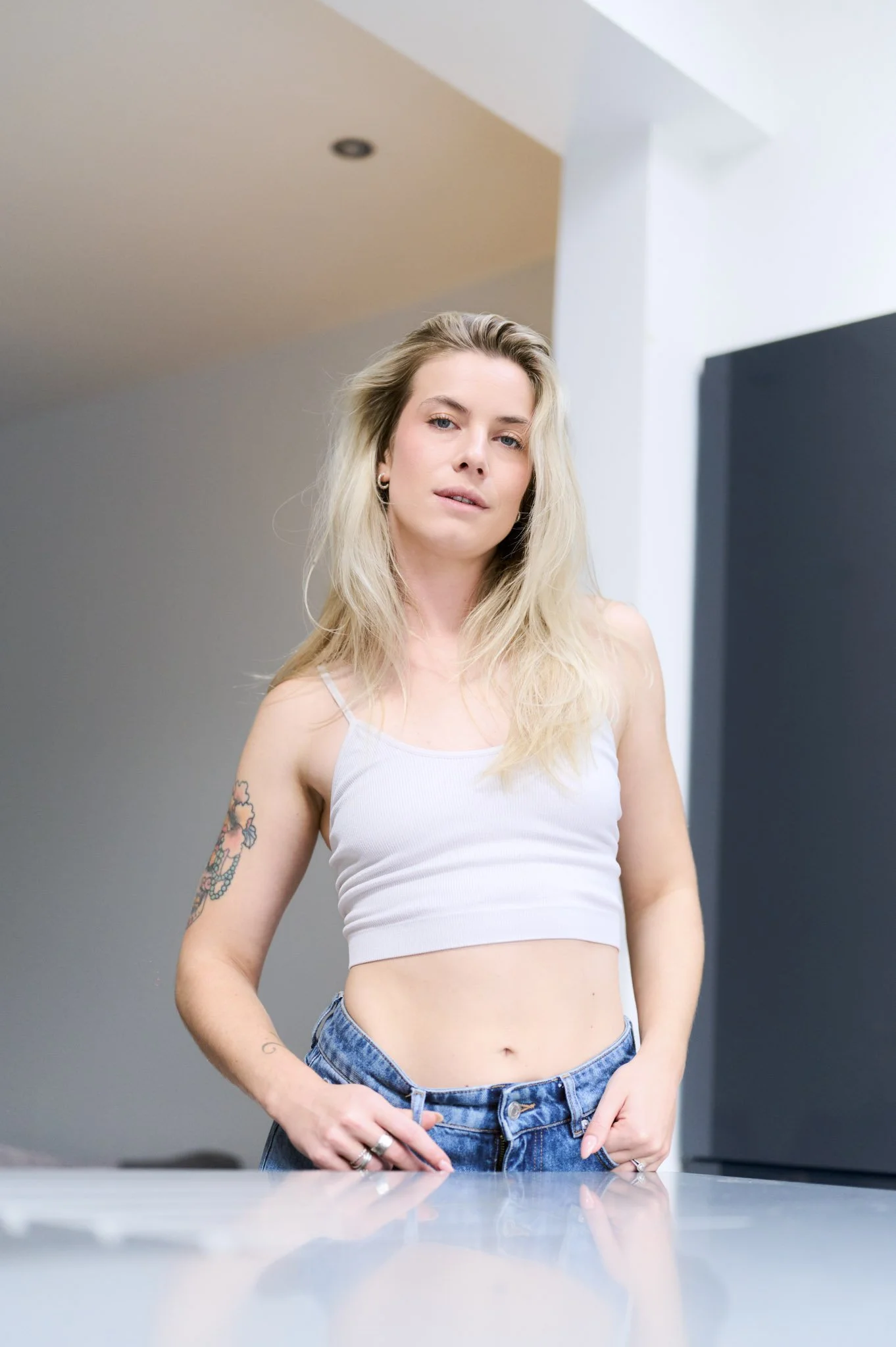Young woman with curly hair wearing a black coat and white crop top standing outdoors.