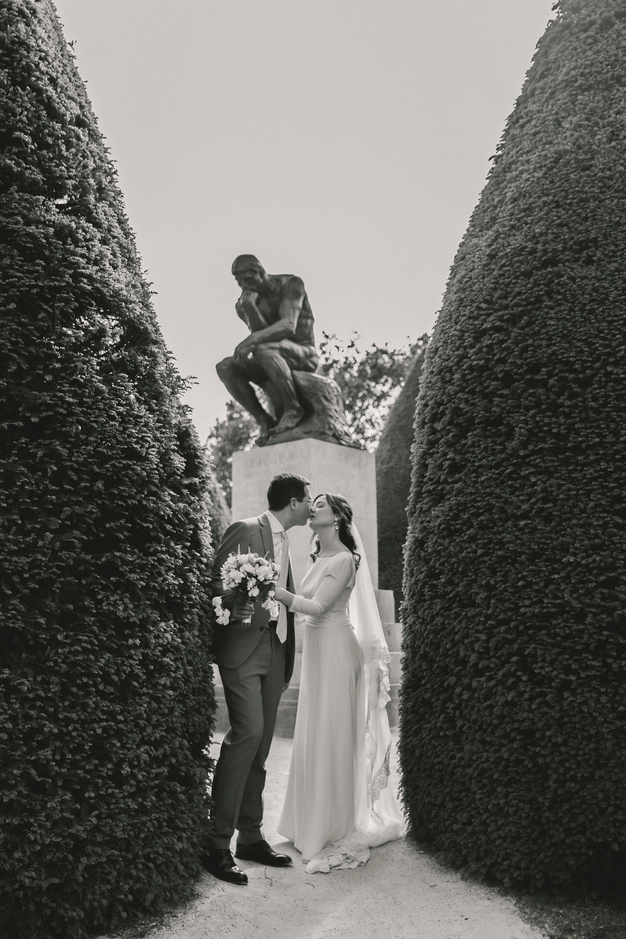 A quiet embrace in the gardens of Musée Rodin, beneath Rodin’s iconic Thinker.