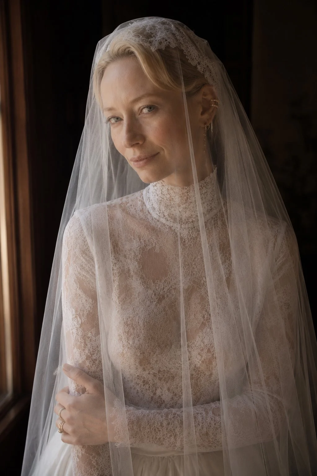 Editorial bridal portrait at Abbaye des Vaux de Cernay in France featuring a bride wearing a delicate lace wedding dress and cathedral veil in soft natural window light.
