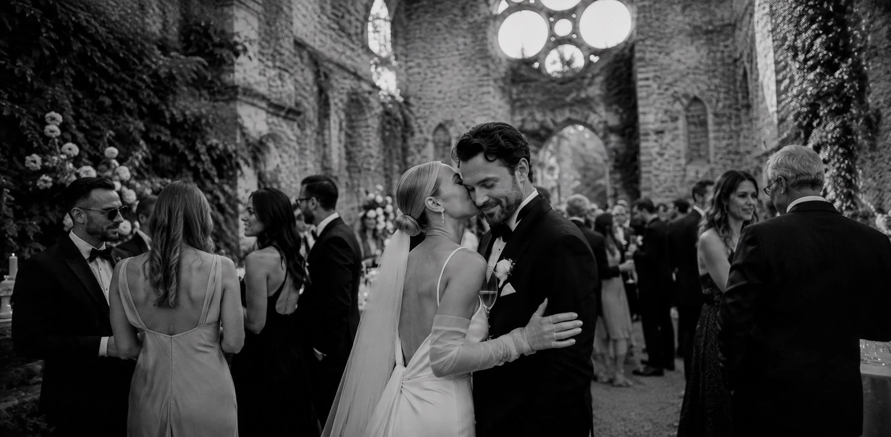 Bride and groom sharing a quiet moment during the cocktail reception at Abbaye des Vaux de Cernay, surrounded by guests beneath the historic abbey ruins.