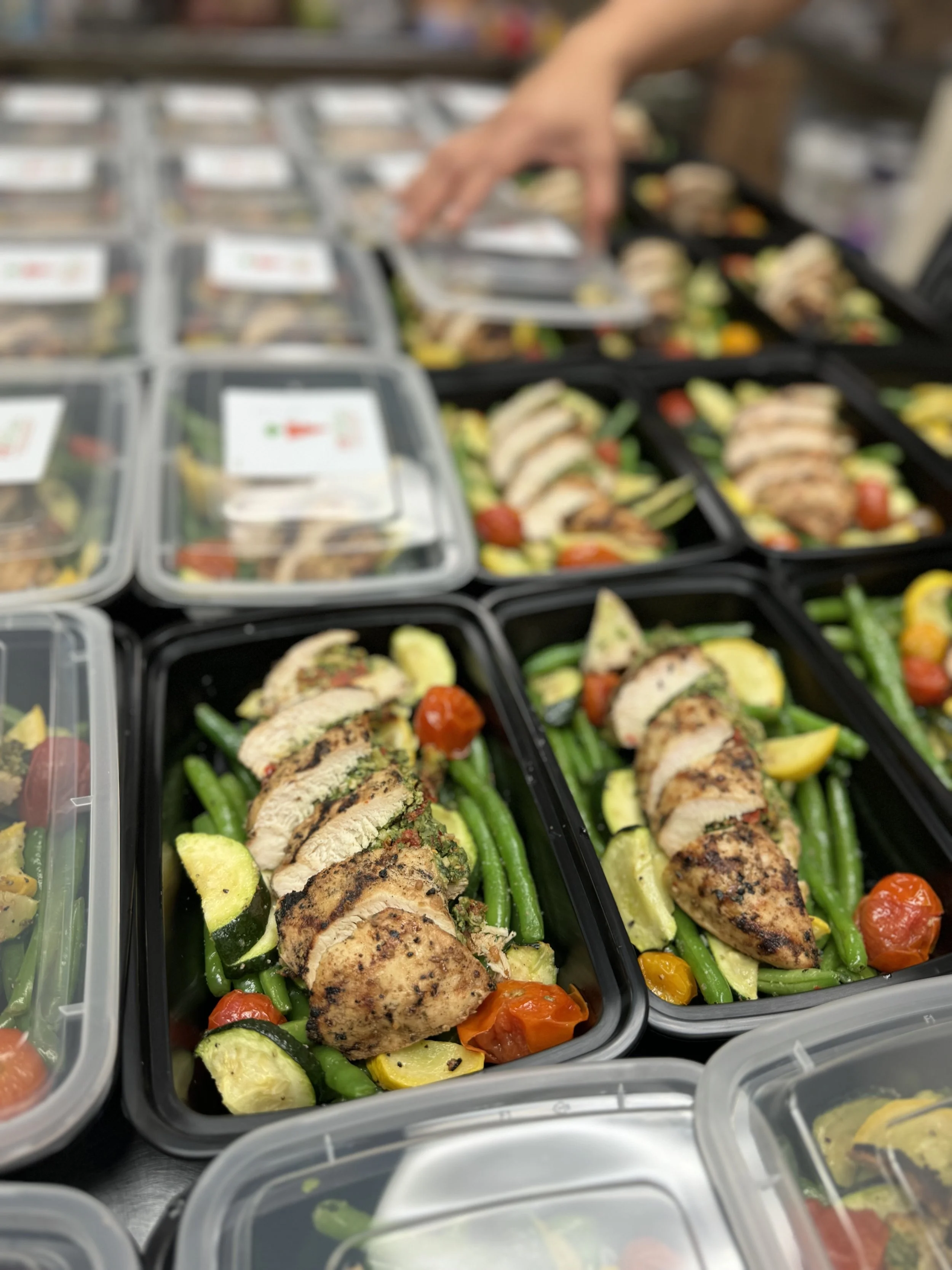Prepared meal containers with grilled chicken, green beans, cherry tomatoes, and yellow squash