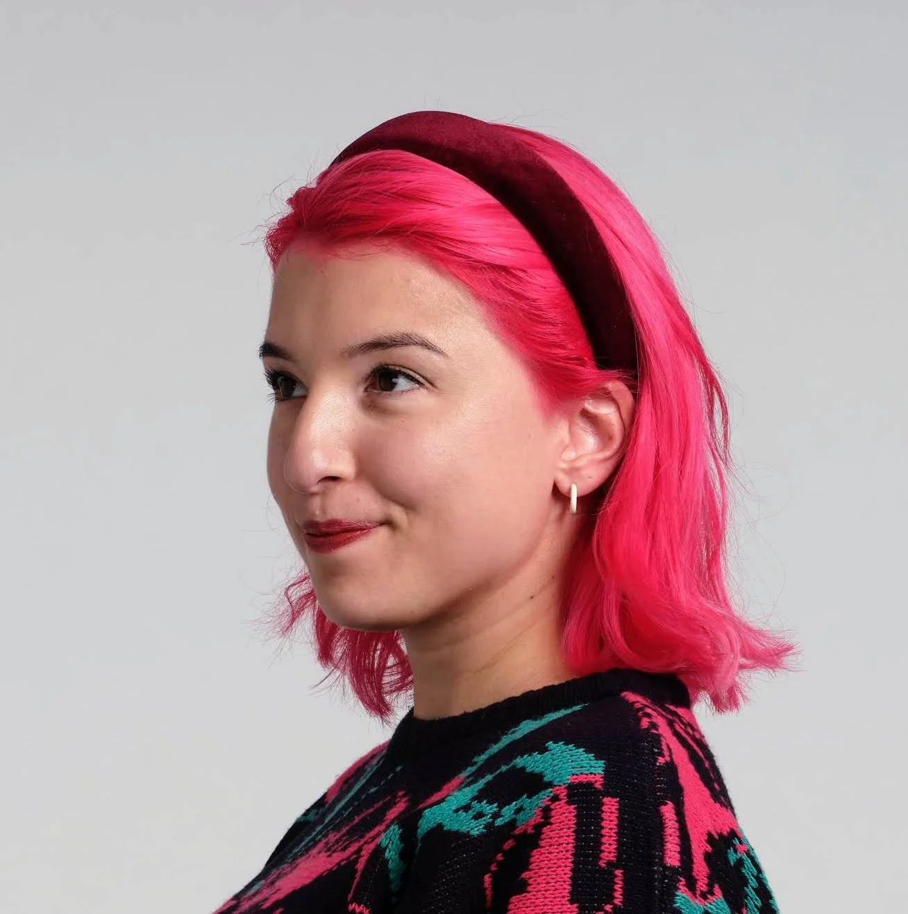 A smiling woman with pink hair.