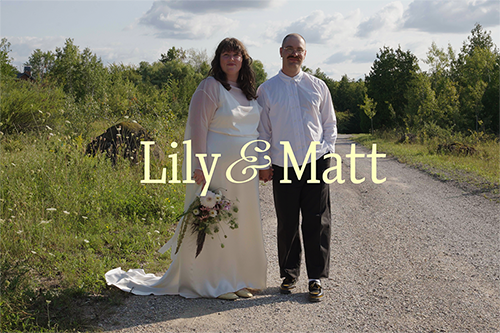 A bride and groom standing on a gravel road in a rural outdoor setting, with trees and green bushes in the background. The bride is holding a bouquet, and the text 'Lily & Matt' is overlaid on the image.