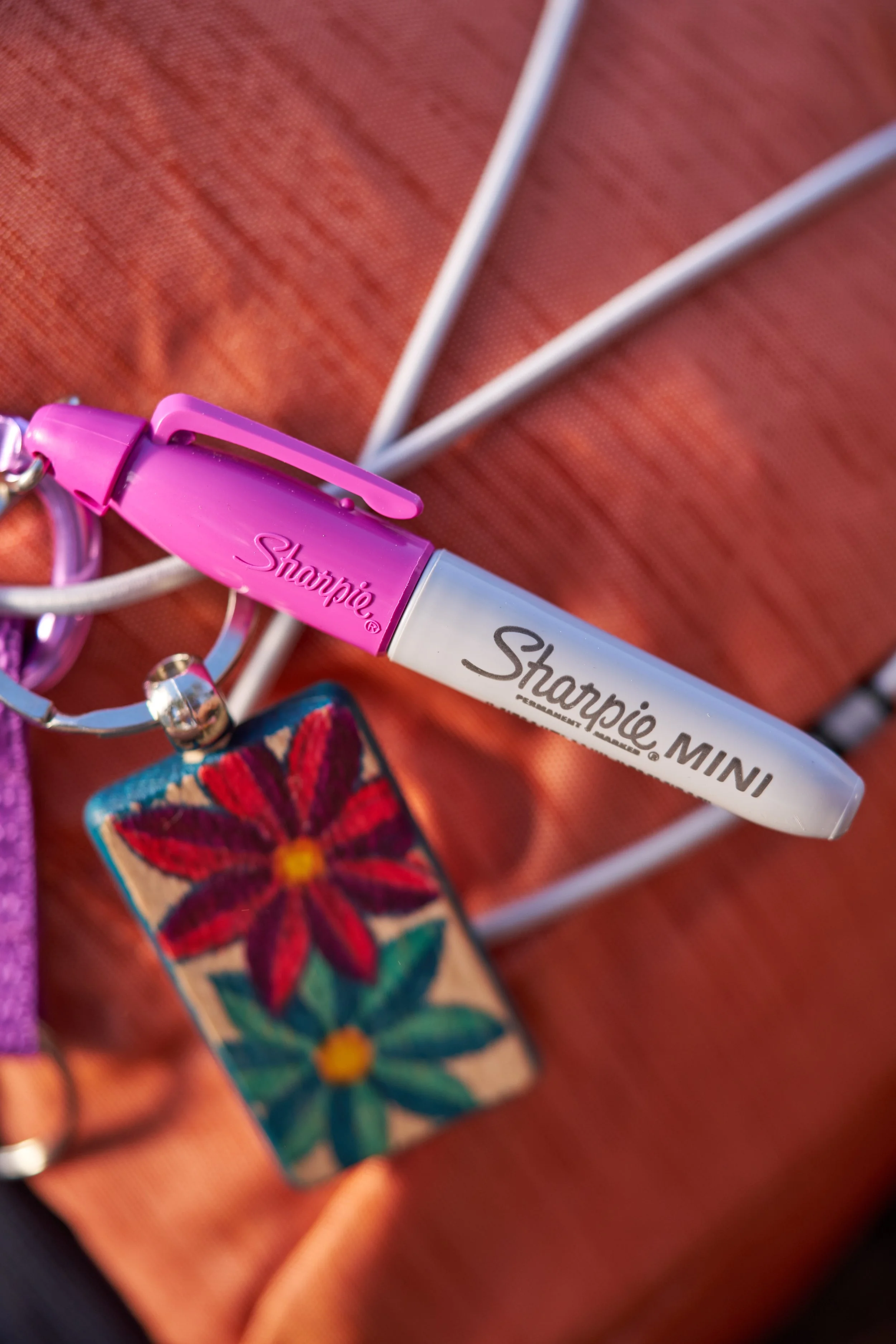 sharpie pens bold horizons mini pink sharpie hanging on backpack next to red flower keychain