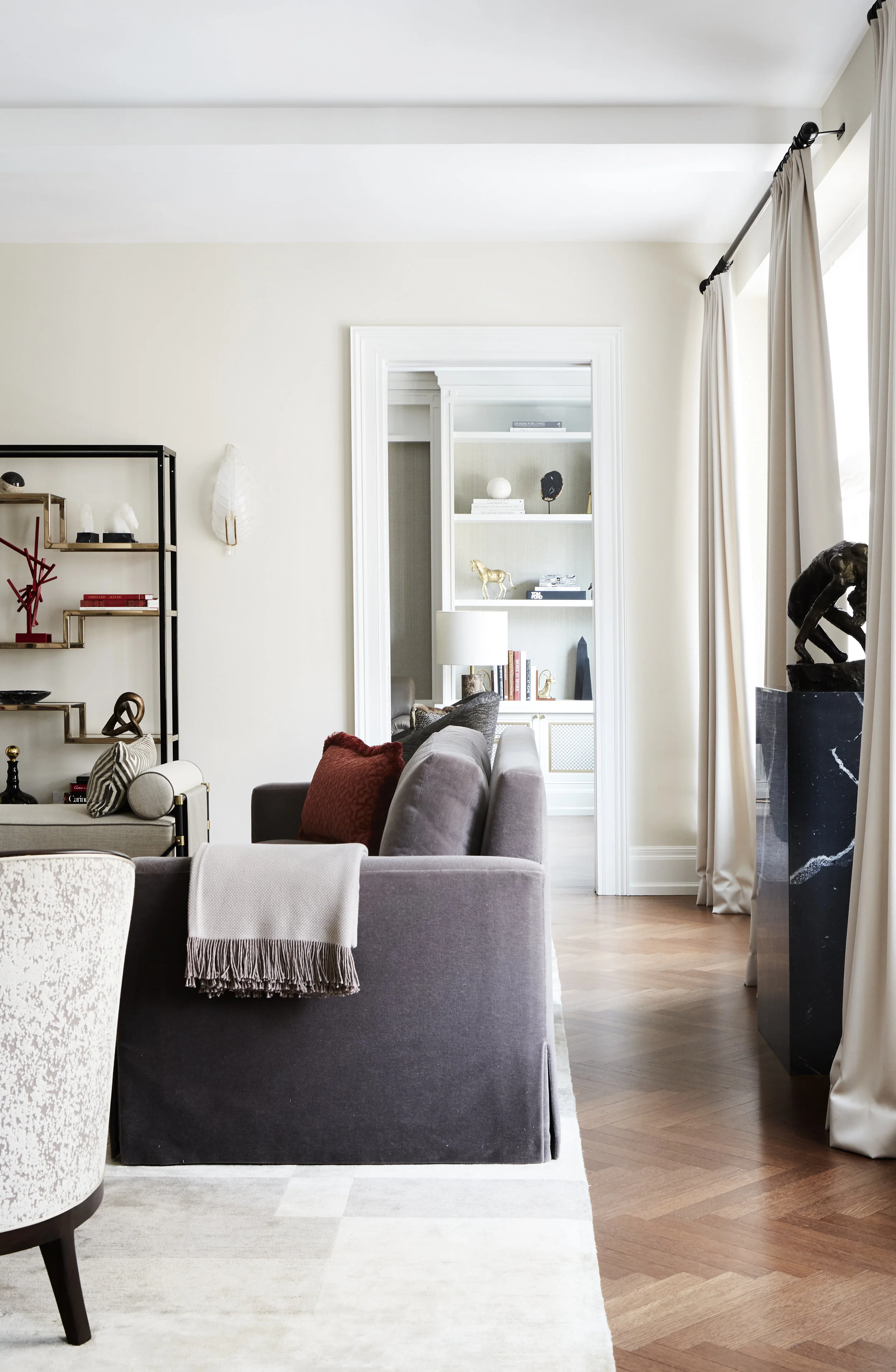 View of living room with gray sofa, book shelves, and a statue
