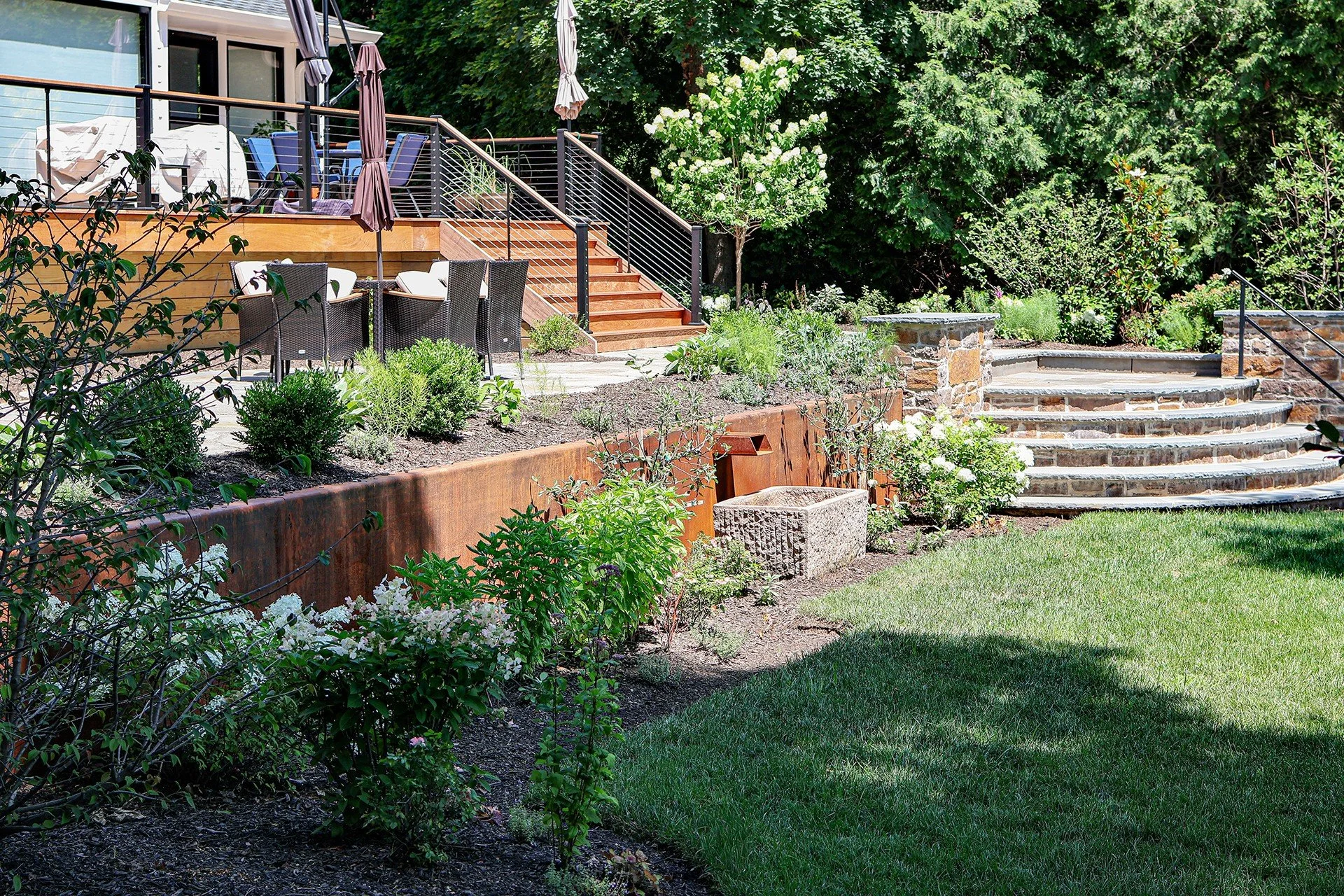 Princeton project, fully realized. This landscape brings together raw materials and refined details: a weathering steel corten retaining wall, a hand-cut fieldstone stacked wall, and custom patios that create layered outdoor living spaces. A carved s