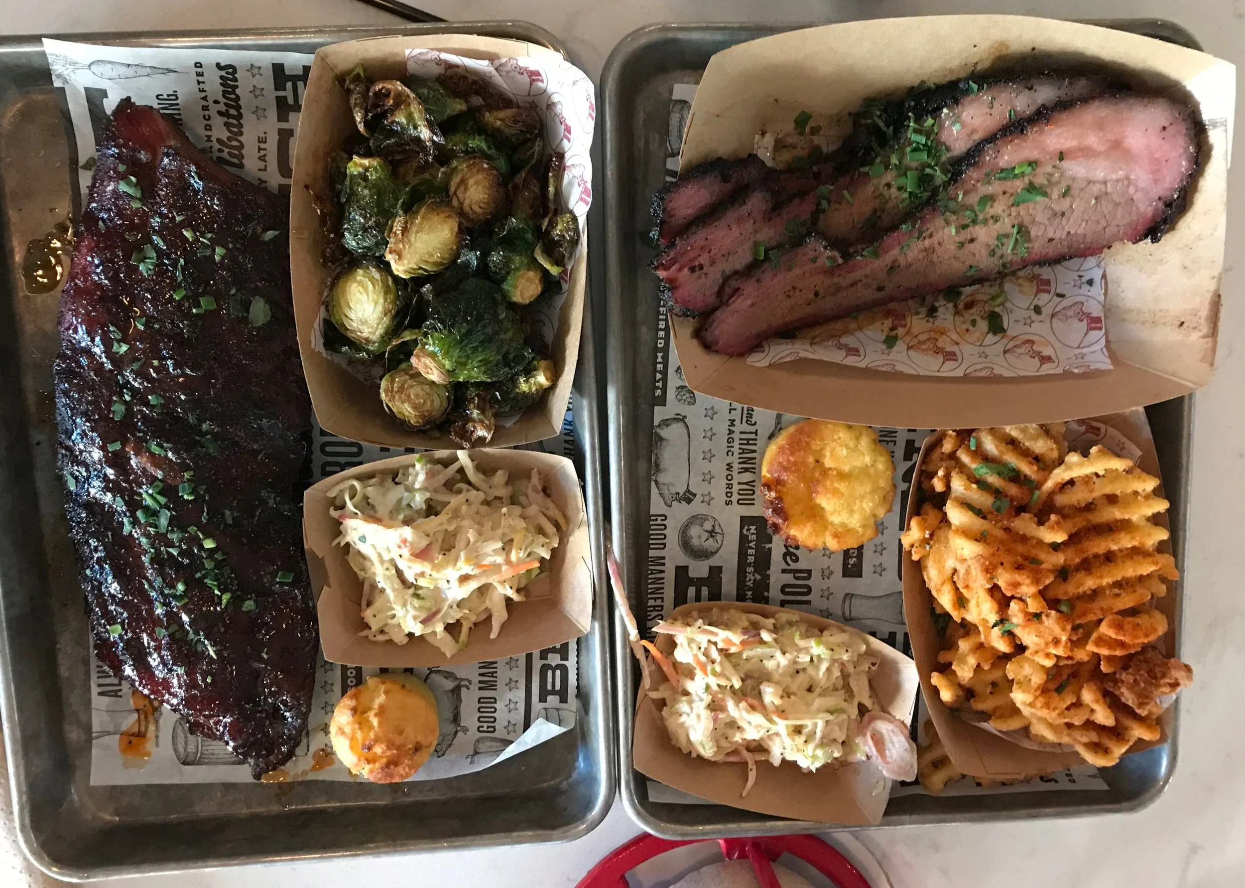 Two Polite Pig counter service meals. Ribs and brisket with waffle fries and Brussel sprouts on the side.