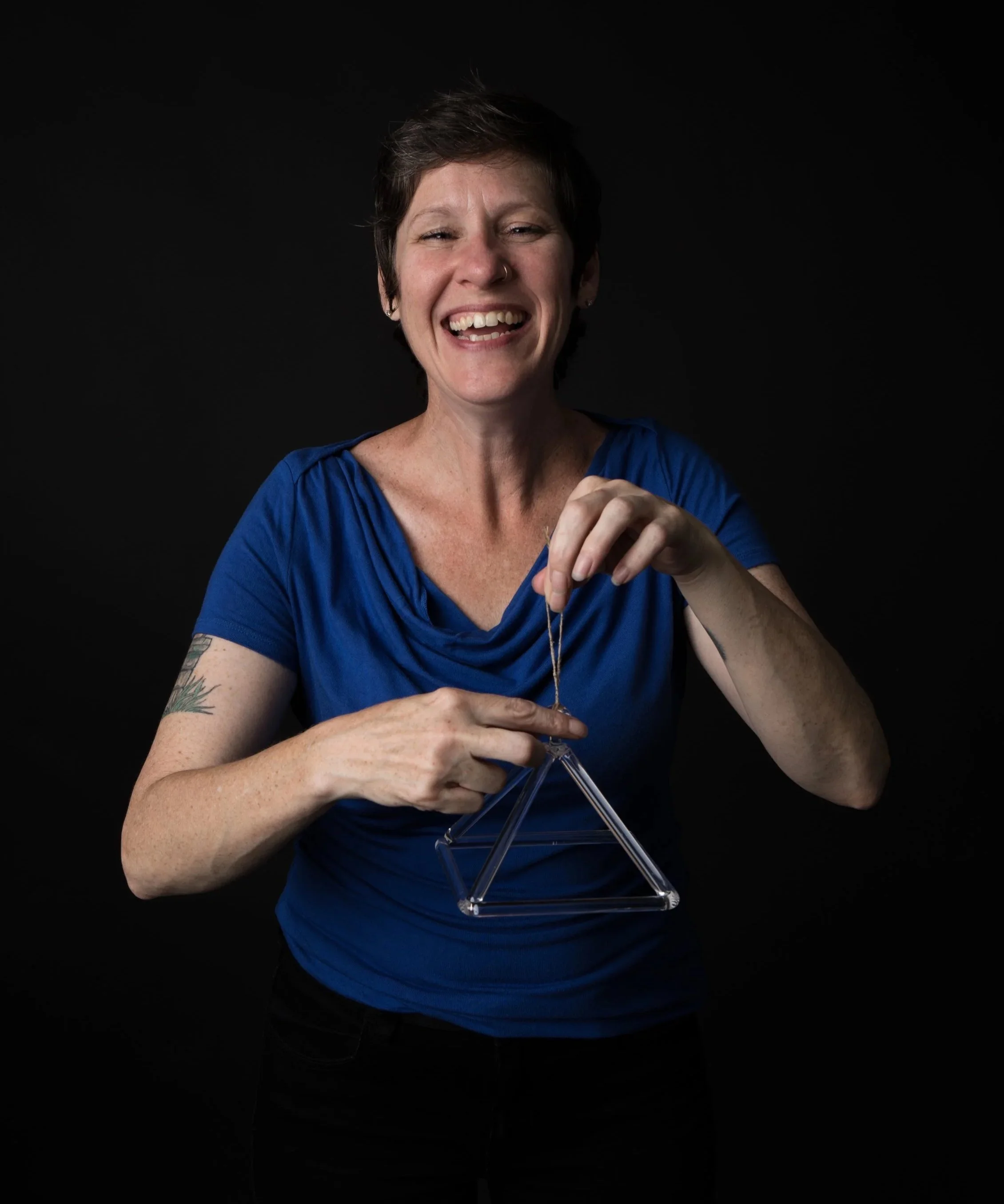 A sound healing professional playing a crystal pyramid.