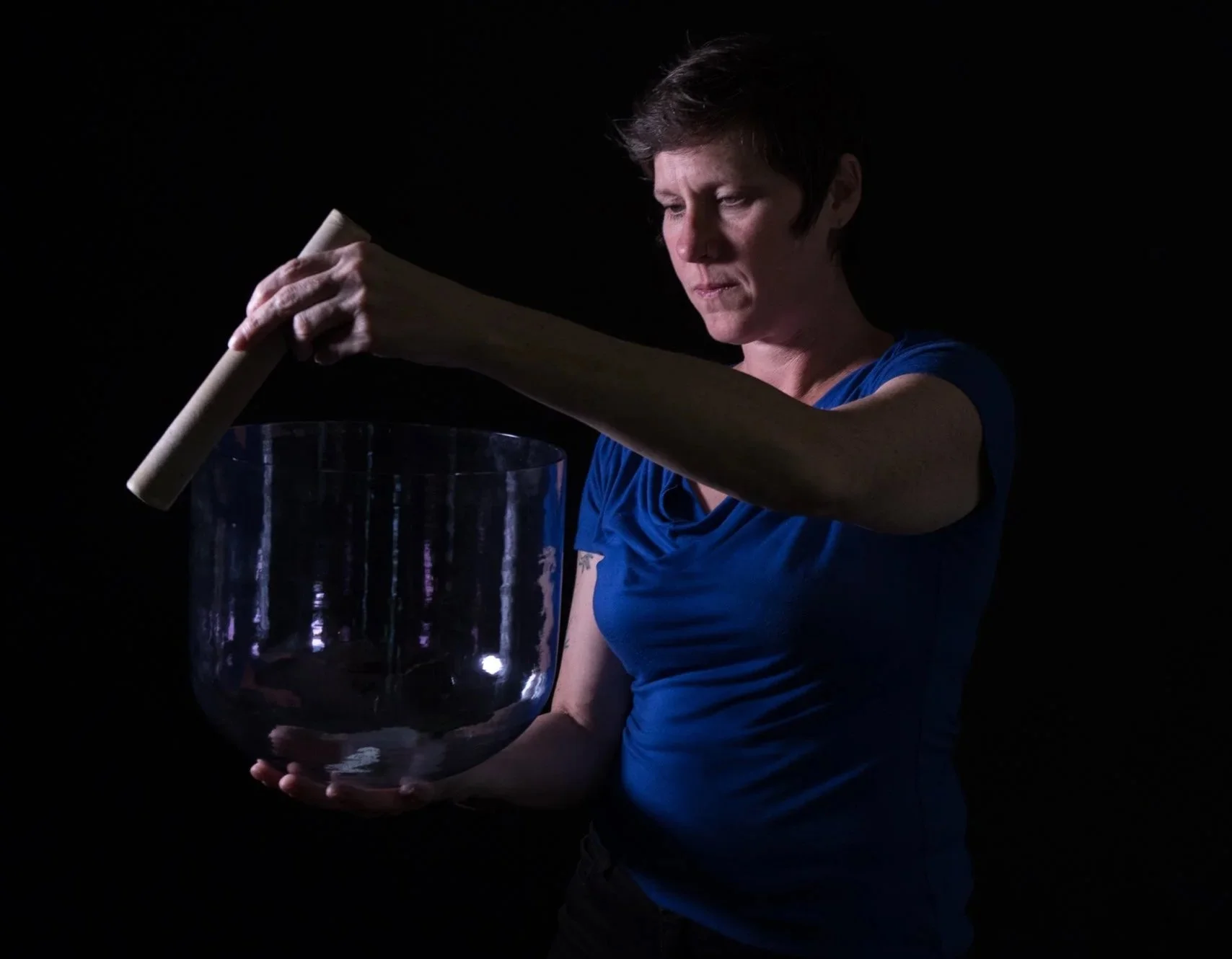A sound healing professional playing a crystal singing bowl.
