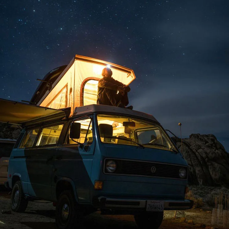 Person sitting on a VW camper van looking at the stars