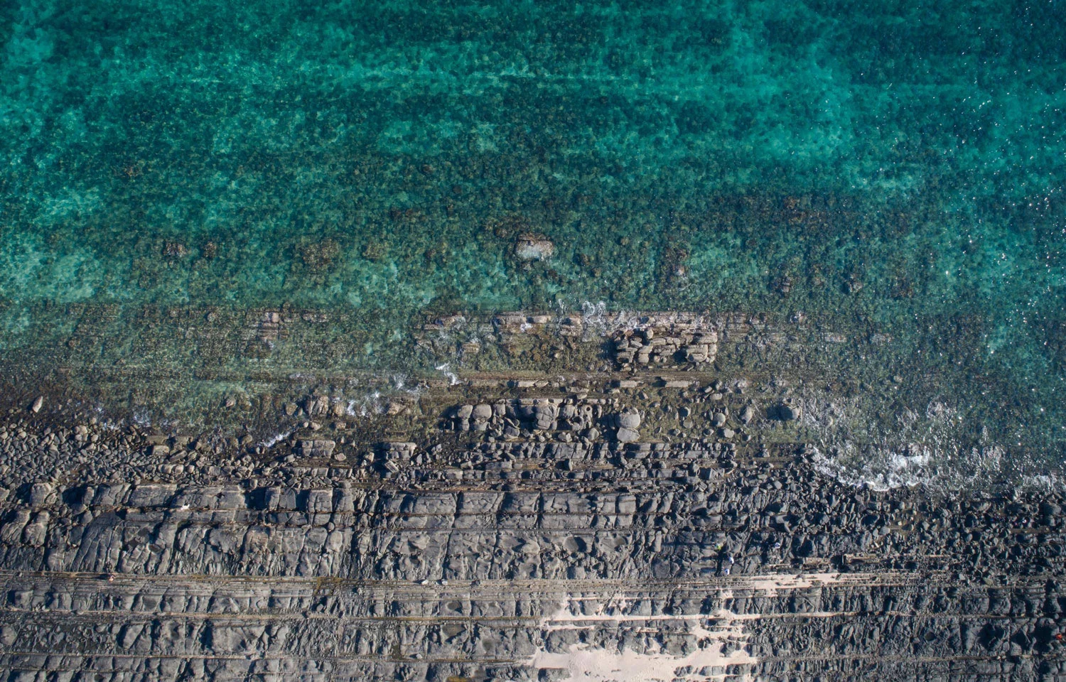 Rocky shoreline against a clear green sea