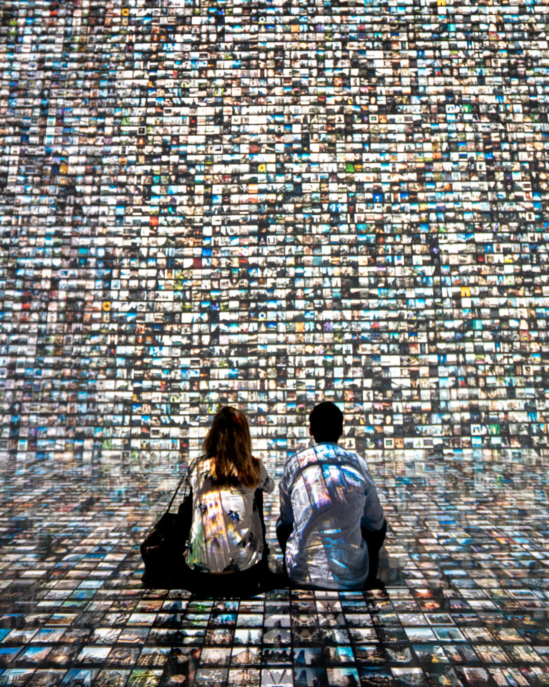Couple sitting on ground with images projected on wall