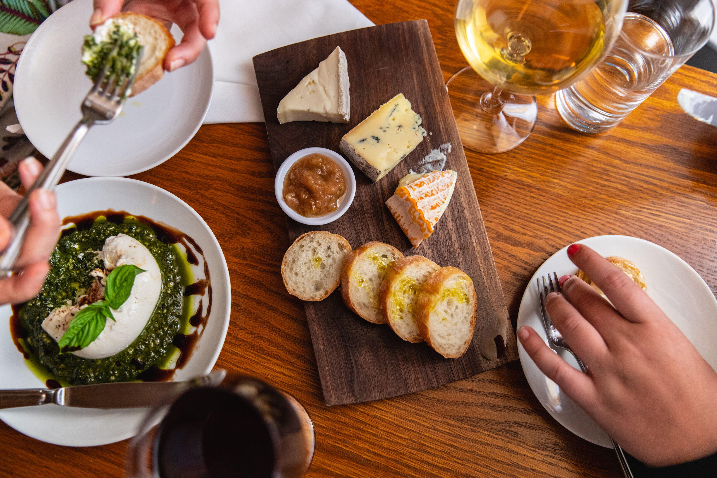 overhead photo of table with cheese spread, burrata, and wine