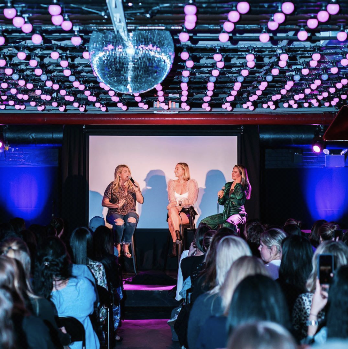 3 people standing on a stage in a dark room preforming for an audience 