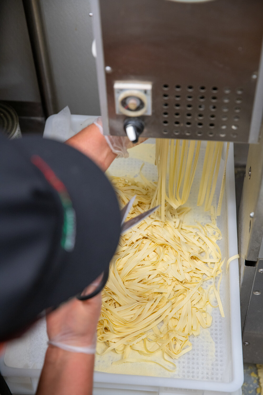 cutting fresh linguine from pasta machine 