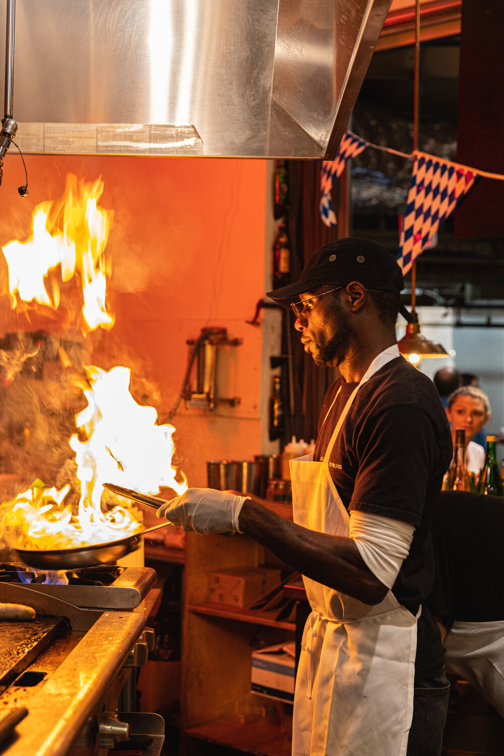 man holding a pan with fire on a stove 