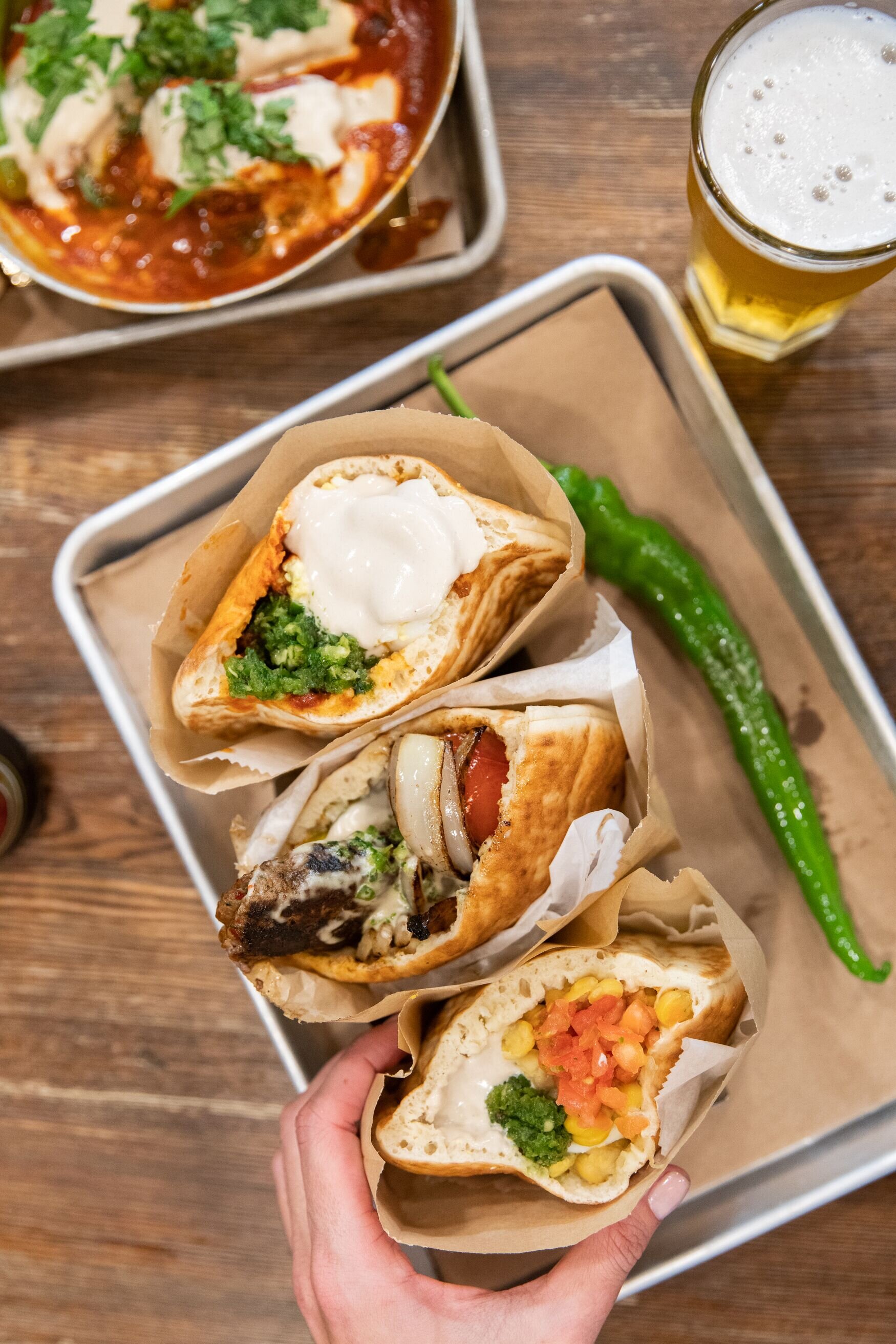 overhead of hand holding a pita, and two pitas in a holder