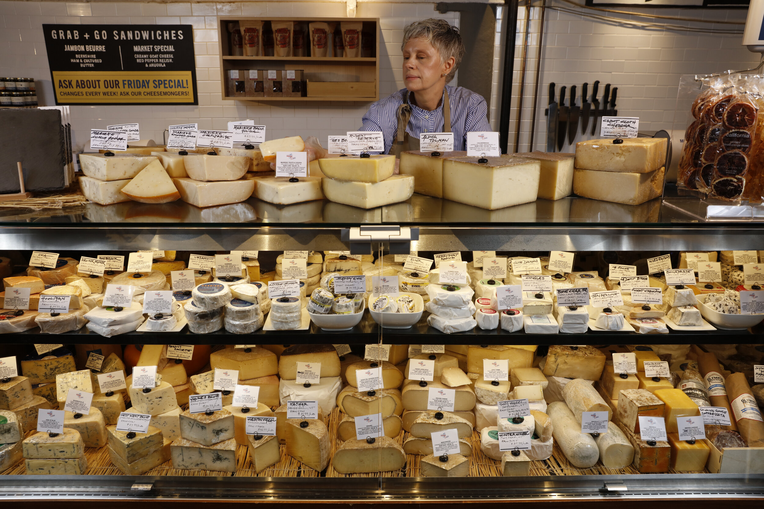 woman standing behind full cheese case 