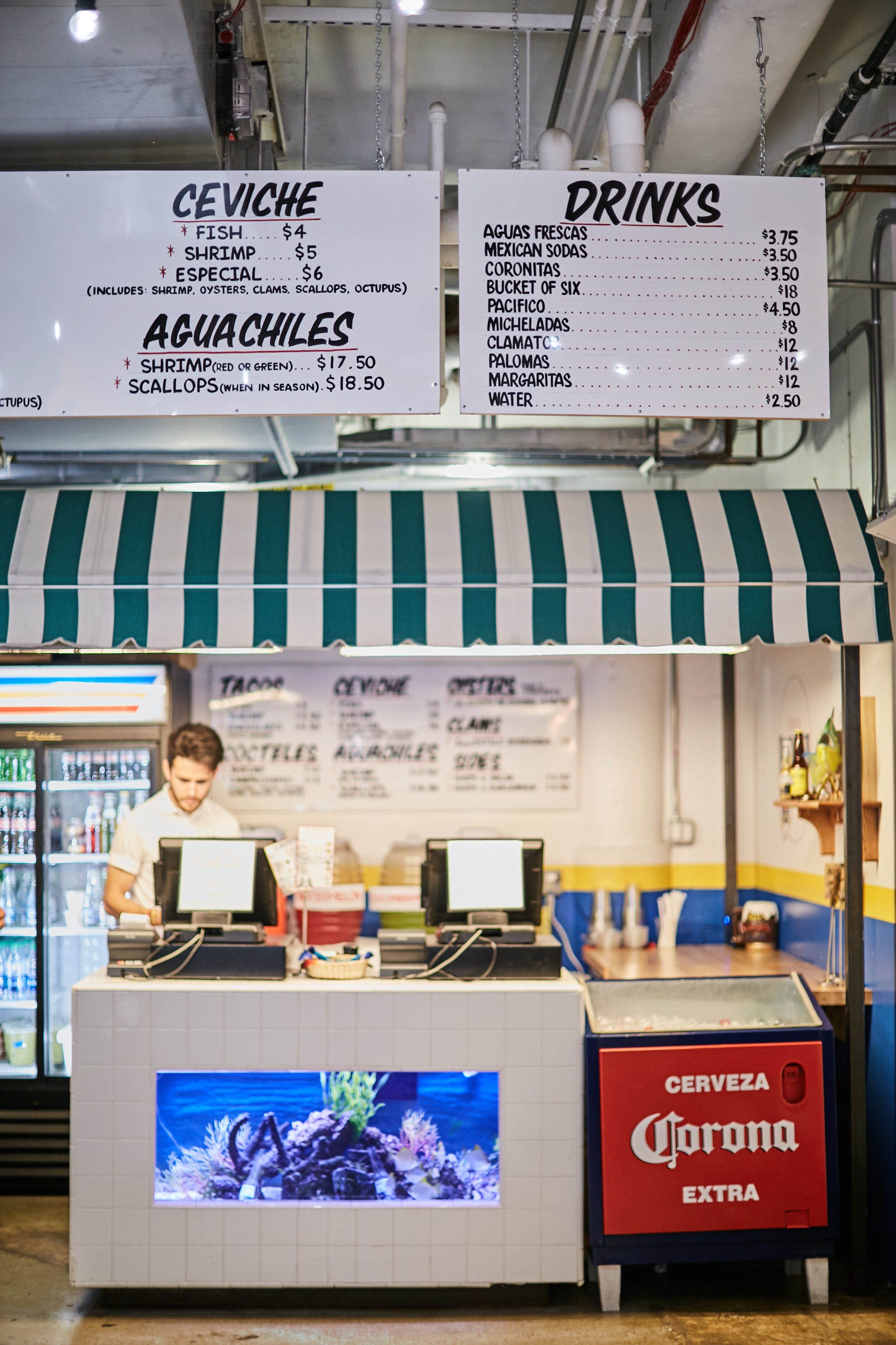 cashier with fishtank below and menu above at los mariscos 