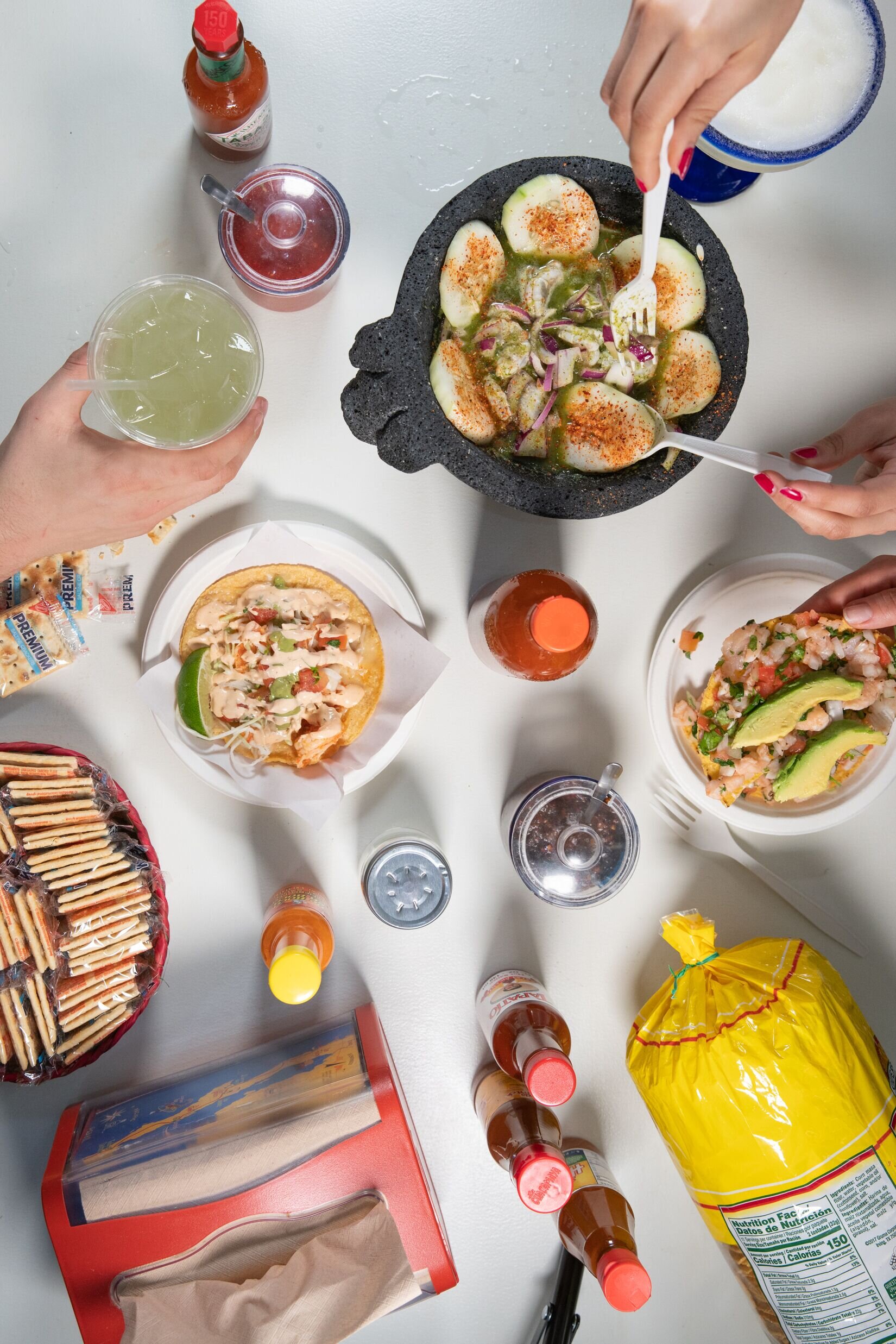 overhead shot of drinks, aguachiles, tacos, and guacamole 