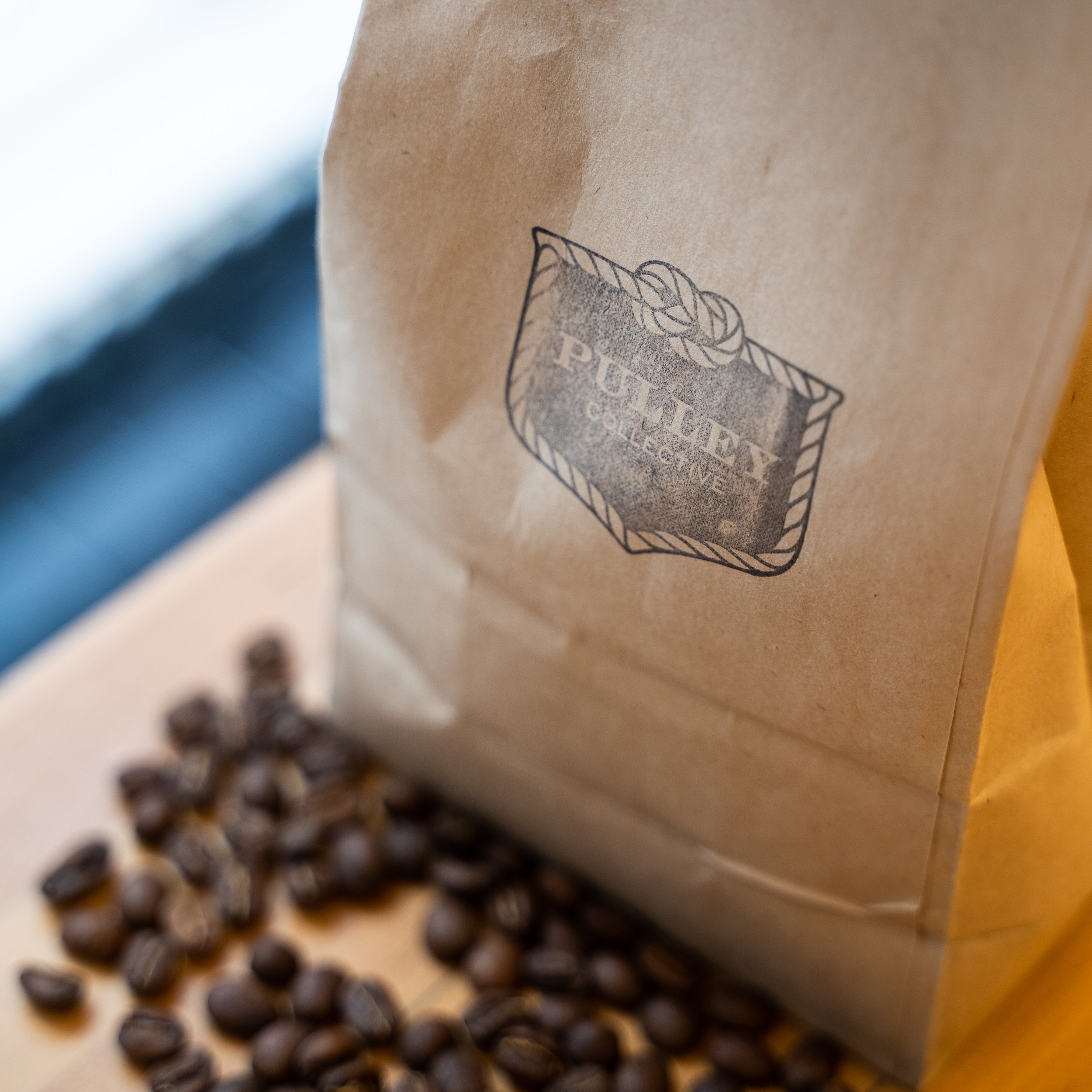 paper bag with logo on top of coffee beans