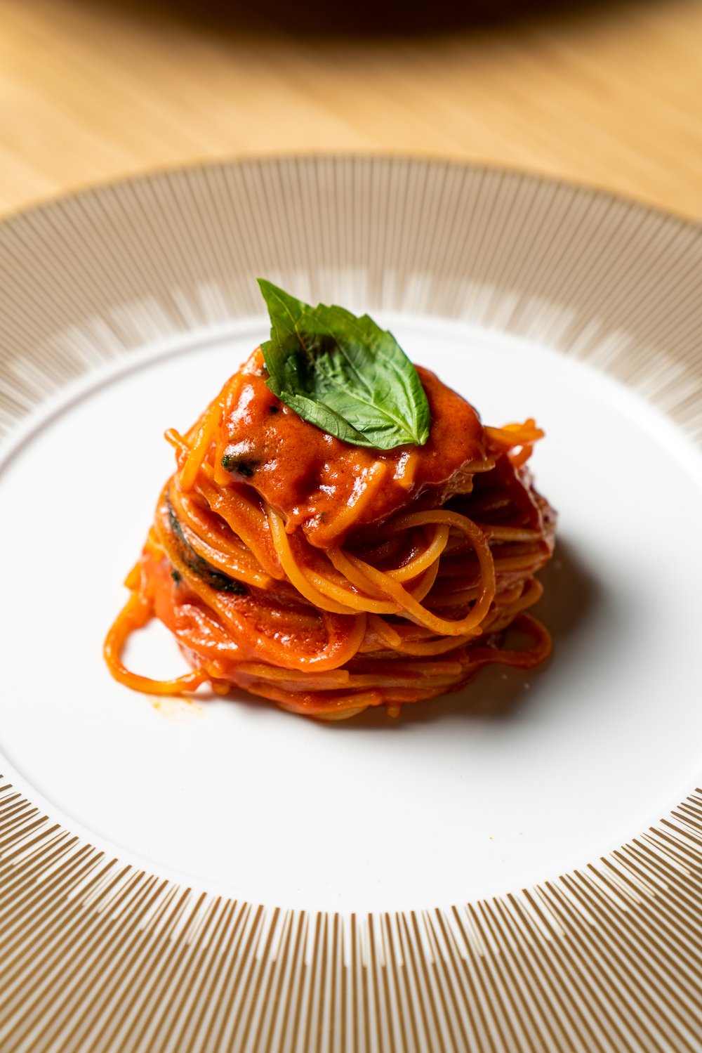 pasta with red sauce topped with basil on white and brown plate