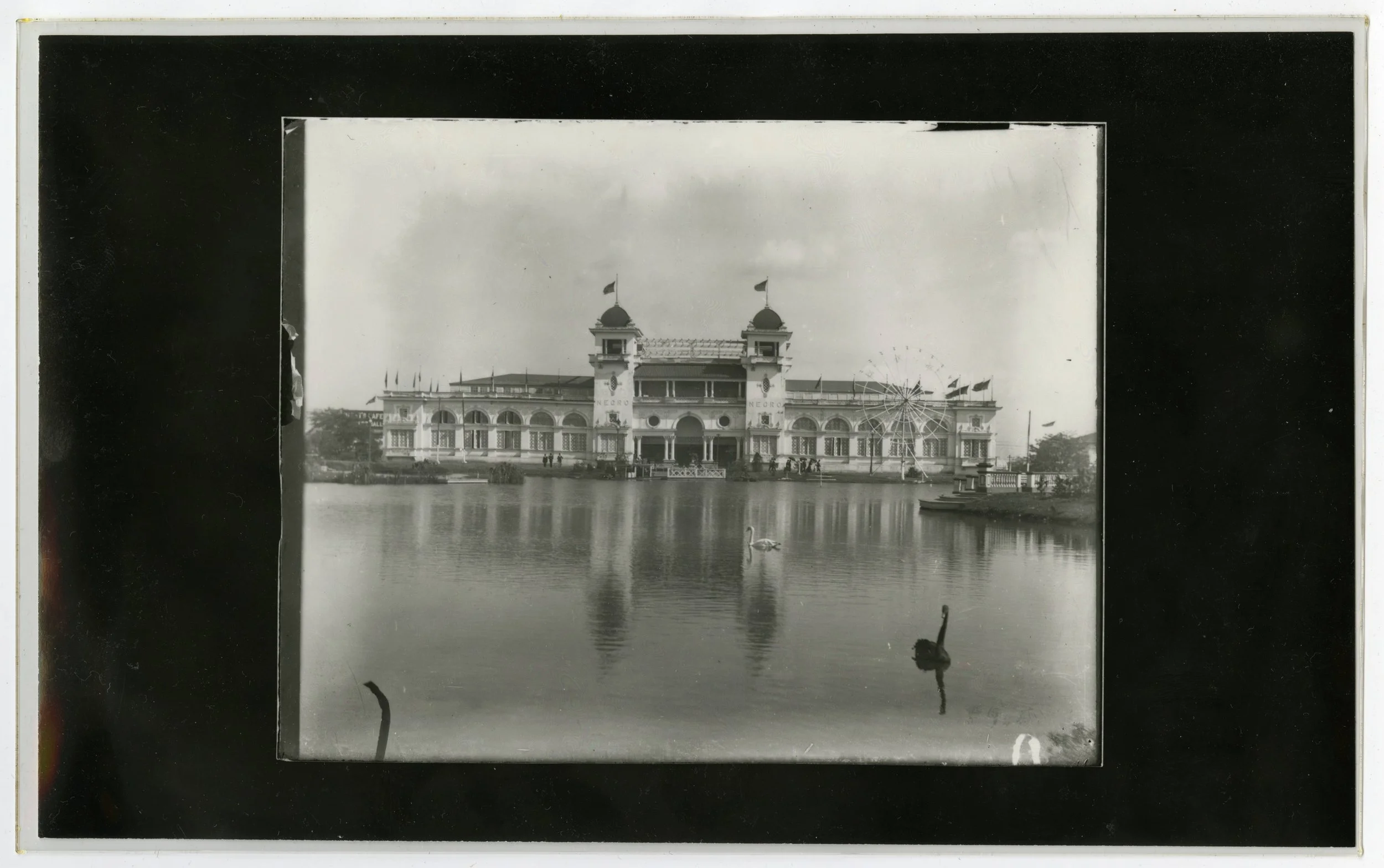 Long shot view of a fairground building with a large body of water in front of it.