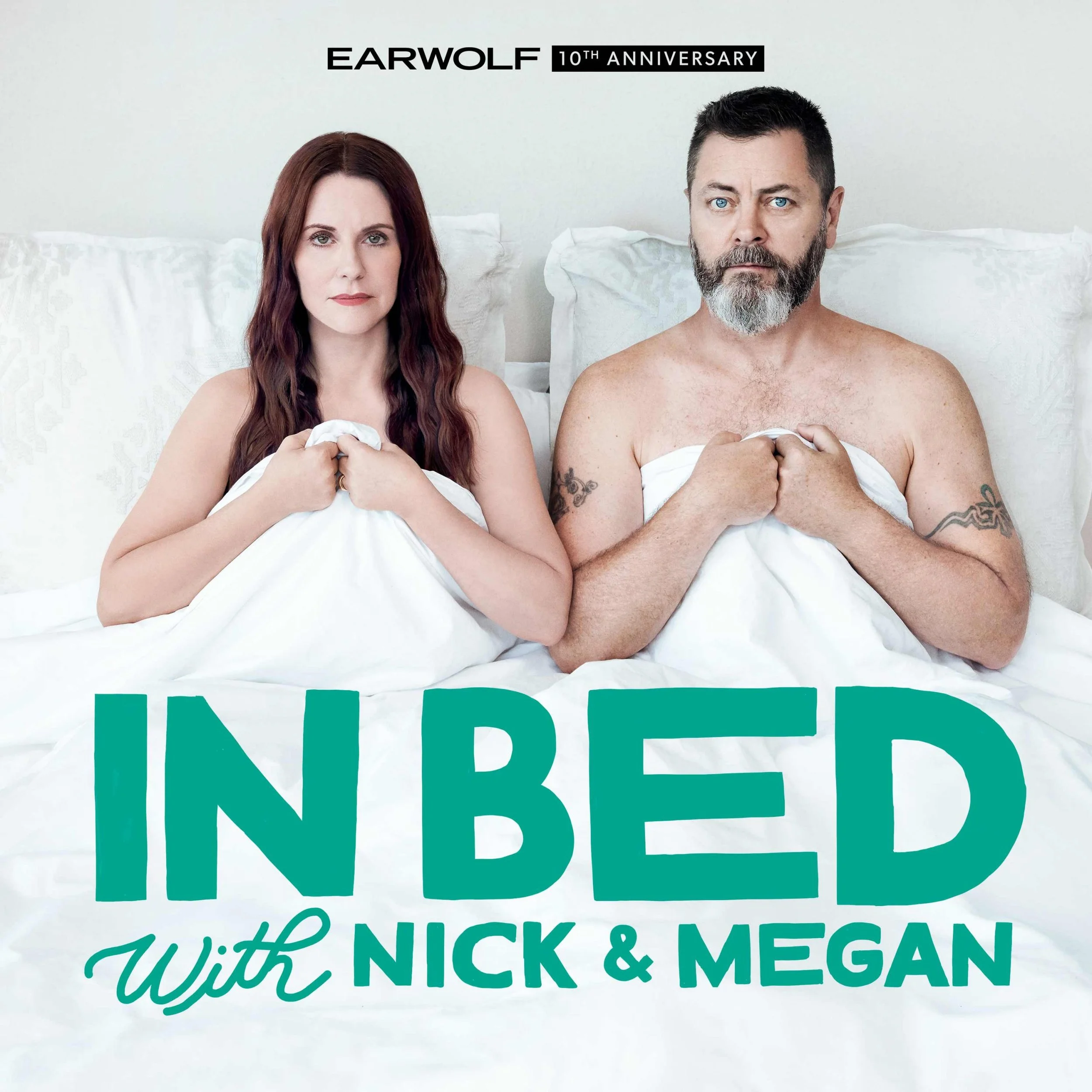 A man and woman sitting in bed, covered with white sheets, looking at the camera. The text on the image says 'Earwolf 10th Anniversary' and 'In Bed with Nick & Megan.'